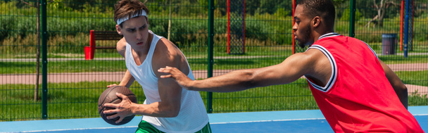 Afrykański amerykański sportowiec wyciąga rękę w pobliżu przyjaciela z piłką do koszykówki, sztandar  - Zdjęcie, obraz