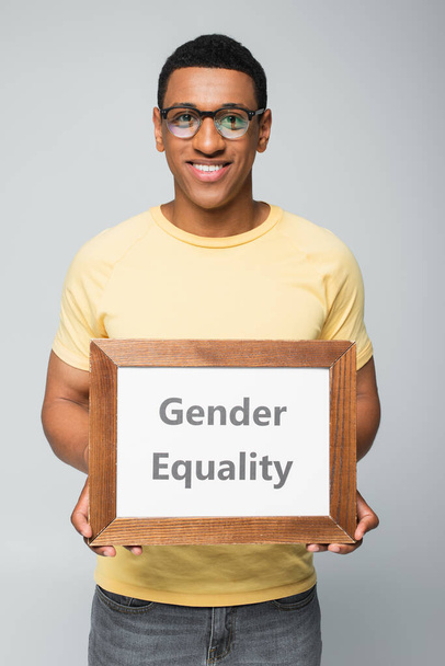 boldog afro-amerikai férfi gazdaság placard nemek közötti egyenlőség betű elszigetelt szürke - Fotó, kép
