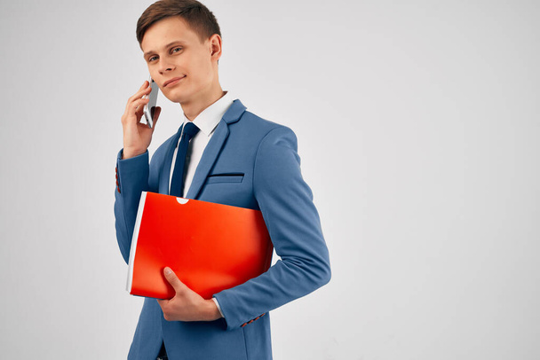 a man in a suit with a red folder a phone in his hands with communication technology - Fotografie, Obrázek