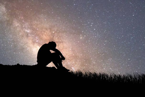 Muž sedí zklamaný láskou k Mléčné dráze a hvězdám v pozadí. koncept ztráty, osamělosti, zklamání - Fotografie, Obrázek
