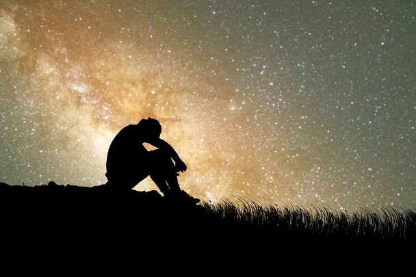 Muž sedí zklamaný láskou k Mléčné dráze a hvězdám v pozadí. koncept ztráty, osamělosti, zklamání - Fotografie, Obrázek