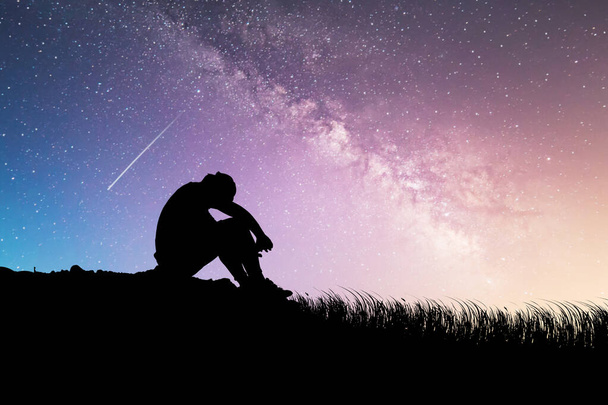 Człowiek siedzi rozczarowany miłością do Drogi Mlecznej i gwiazdami w tle. pojęcie straty, samotności, rozczarowania - Zdjęcie, obraz