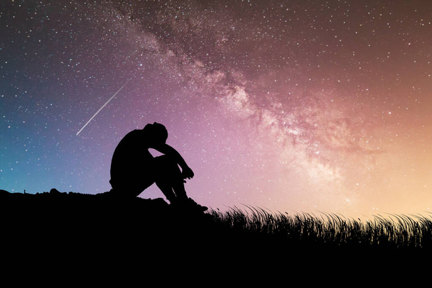 Een man is teleurgesteld in de Melkweg en sterren op de achtergrond. begrip verlies, eenzaamheid, teleurstelling - Foto, afbeelding