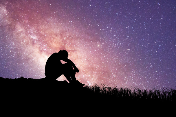 Мужчина сидит разочарованный в любви к Млечному Пути и звездам на заднем плане. концепция потери, одиночества, разочарования - Фото, изображение