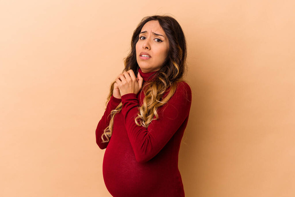 Genç Meksikalı hamile kadın bej arka planda izole edilmiş korkmuş ve korkmuş.. - Fotoğraf, Görsel