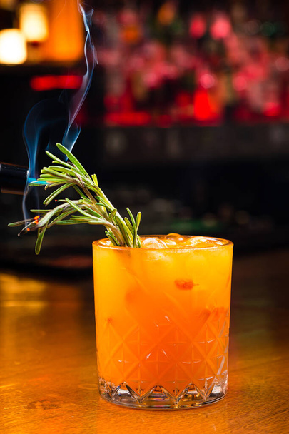 gin and tonic sea buckthorn cocktail with rosemary. Refreshing summer drink Sea-buckthorn juice in glass, decorated with rosemary and smoke - Foto, Imagem