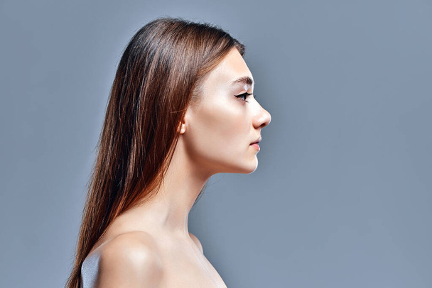 Side view of beautiful young woman with clean perfect skin. Beauty model portrait with natural nude makeup. Spa, skin care and wellness. Close up, gray background, copyspace. - Φωτογραφία, εικόνα