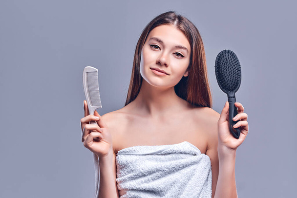 Portrait of a beautiful attractive cute well-groomed lady holding a comb in her hand, smooth, soft, silky hair, keratin effect, isolated on gray background. - Photo, Image