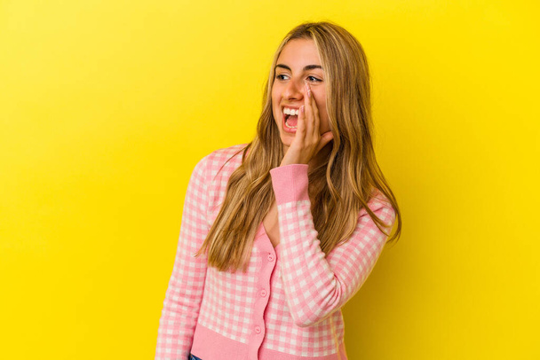 Young blonde caucasian woman isolated on yellow background shouting excited to front. - Foto, Imagem