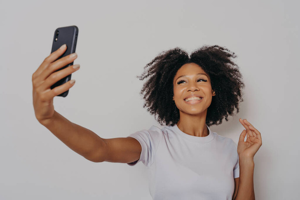 Θετική χαρούμενη σκουρόχρωμη γυναίκα κάνοντας φωτογραφία στη σύγχρονη κάμερα smartphone - Φωτογραφία, εικόνα