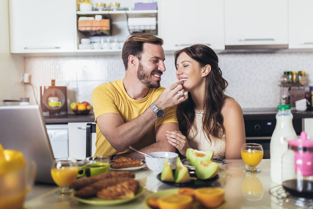 Happy couple having breakfast together in the kitchen - Photo, Image