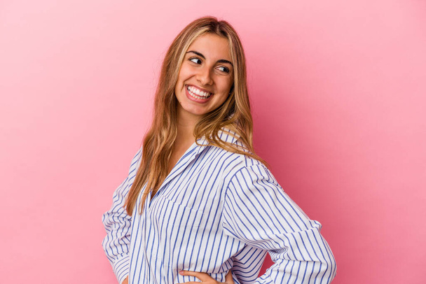 Young blonde caucasian woman isolated on pink background laughs happily and has fun keeping hands on stomach. - Photo, Image