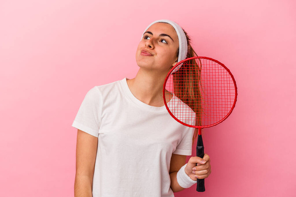 Young cute blonde caucasian woman holding a badminton racket isolated on pink background dreaming of achieving goals and purposes - Photo, Image
