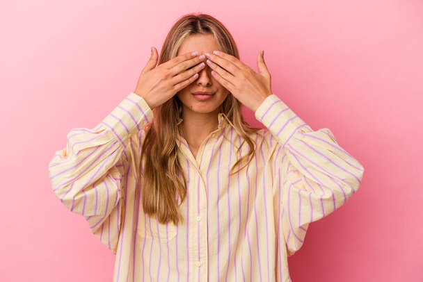 Young blonde caucasian woman isolated on pink background afraid covering eyes with hands. - Foto, imagen