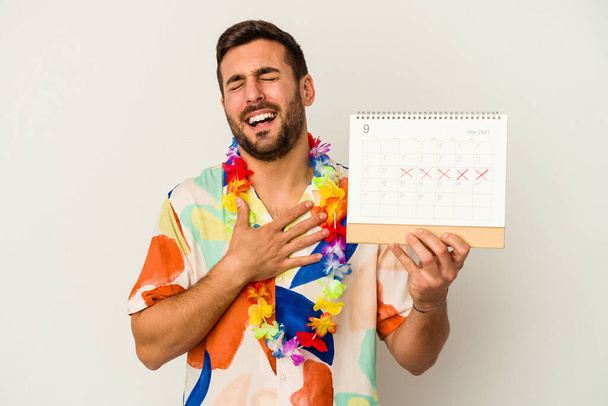 Mladá běloška čeká na jeho dovolenou s kalendářem izolované na bílém pozadí se hlasitě směje držet ruku na hrudi. - Fotografie, Obrázek