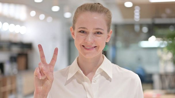 Портрет позитивной предпринимательницы, показывающий знак победы от руки  - Фото, изображение