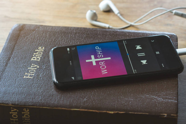 Біблія з телефоном і навушниками, Концепція слухає слова God.Bible, телефон і навушники на дерев'яному столі. - Фото, зображення