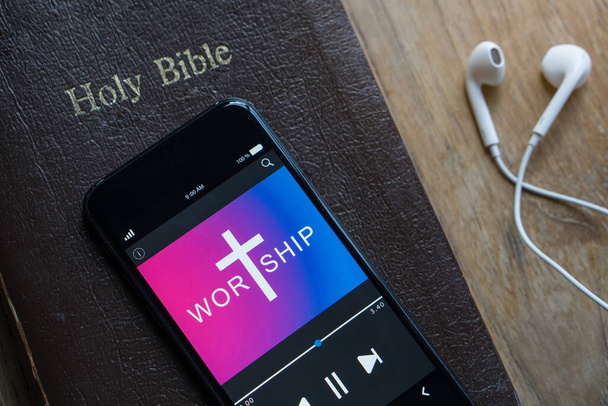 Biblia z telefonem i słuchawkami, Concept słuchać słów Boga.Biblia, telefon i słuchawki na drewnianym stole. - Zdjęcie, obraz