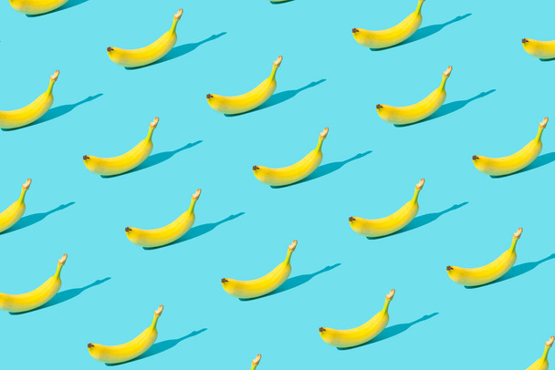 Trendikäs auringonvalo Kesäkuvio, joka on valmistettu tuoreista banaanihedelmistä kirkkaan vaaleansinisellä taustalla. Minimaalinen kesäkonsepti. - Valokuva, kuva