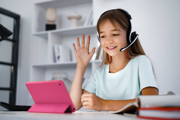 Little caucasian girl in headphones have video call distant class with teacher at home - Foto, Bild