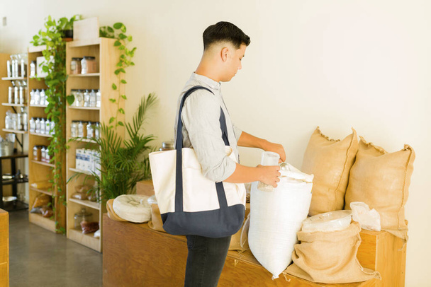 Meine Haferflocken sind bio. Umweltbewusster junger Mann und Verbraucher kaufen Mehl in einem kunststofffreien Großhandel - Foto, Bild