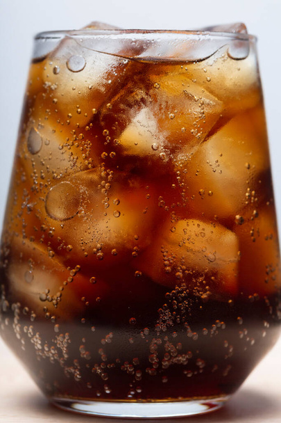 rum met cola en ijs in een glas close-up, cola met ijs. zomerdrankje - Foto, afbeelding