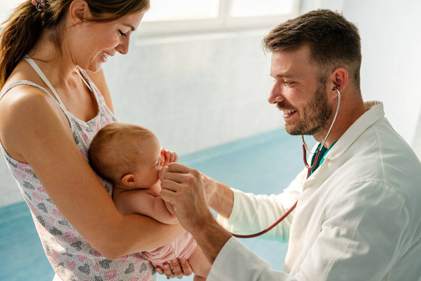 Mother holding baby for pediatrician doctor to examine. People healthcare concept - Фото, изображение