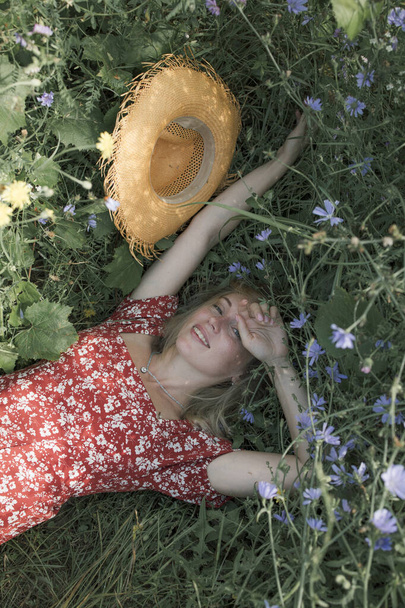 Kız dinleniyor, çimenlere uzanıyor, elini güneşten koruyor. - Fotoğraf, Görsel