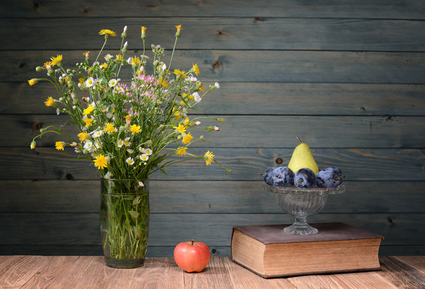 Flowers in a vase, books and fruit - Photo, Image