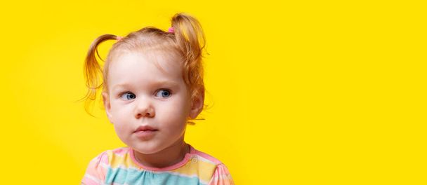 Cidden bebek kız boş sarı arka plana bakıyor, metin için yeri olan panoramik düzen - Fotoğraf, Görsel