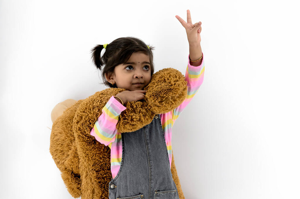 Ritratto di bambino caucasico di quattro anni mostra due dita per mostrare il numero due o firmare la vittoria guardando lontano dalla fotocamera con sfondo bianco - Foto, immagini