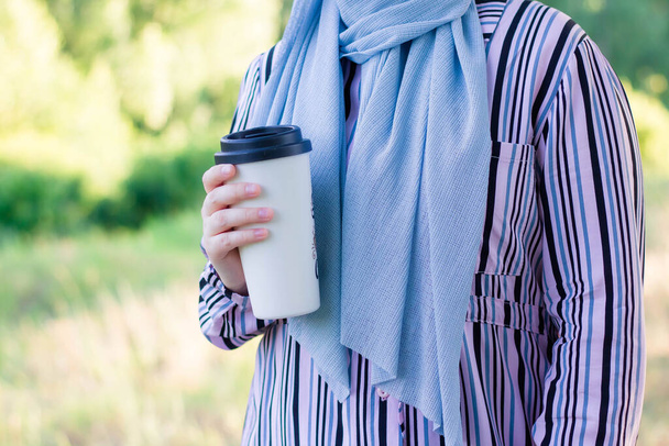 Muslim woman in hijab with white cup of coffee. Hike in the woods. Travels. Pink backpack. - Fotografie, Obrázek