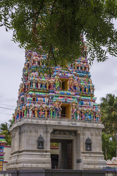Indian Temple torni lähikuva täydelliset arkkitehtuurin yksityiskohdat. Monivärinen temppeli torni Etelä-Intiassa puiden ympäröimänä - Valokuva, kuva