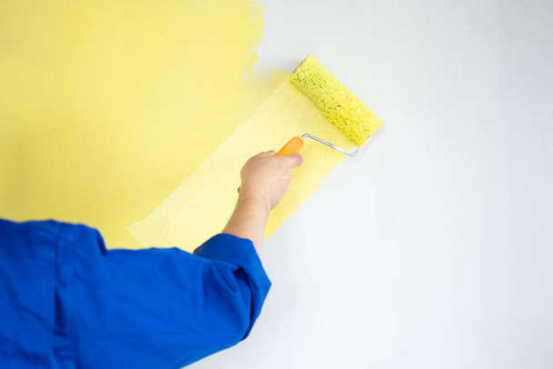 mur de peinture homme de couleur jaune avec rouleau. Concept de rénovation, réparation et redécoration. - Photo, image