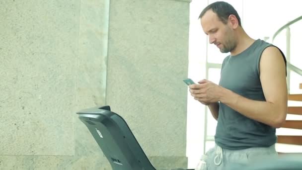 Hombre mensajes de texto en el teléfono inteligente en el gimnasio
 - Metraje, vídeo