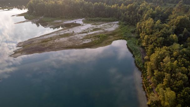 Aerial view shot by a drone of the shore of a forest lake. Thick grass, reflections in the water, green birches in the distance on the slope. Nature of the Blakheide, Beerse, Belgium - Photo, Image