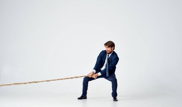 un hombre en un traje tira de la cuerda carrera oficina luz fondo - Foto, Imagen
