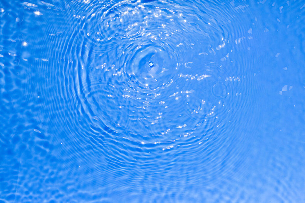 Superfície de azul transparente piscina textura da água com círculos na água. Fundo de natureza abstrata na moda. Ondas de água em reflexos de luz solar. - Foto, Imagem