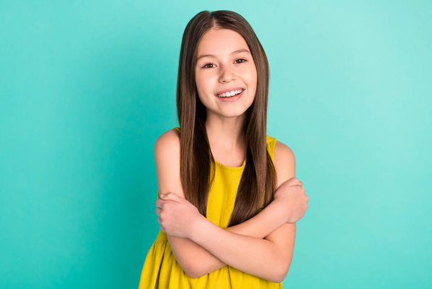 Photo of optimistic nice brown hair girl hug herself wear yellow dress isolated on bright teal color background - 写真・画像