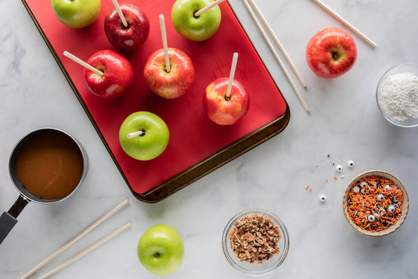 Сверху вниз вид яблок на сковороде в окружении ингредиентов, чтобы сделать карамельные яблоки на Хэллоуин. - Фото, изображение