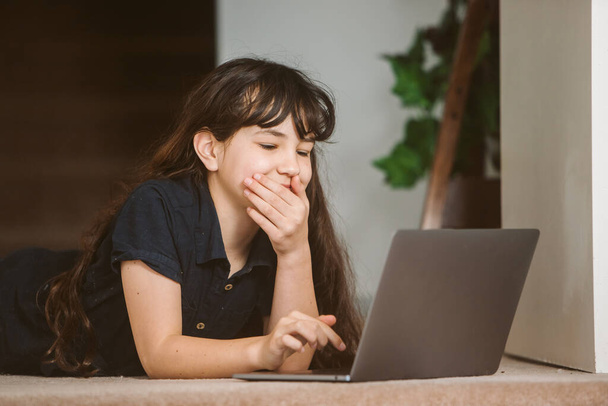 portrait of cute child girl doing on-line learning using laptop, home schooling, distant learning - Foto, Imagen