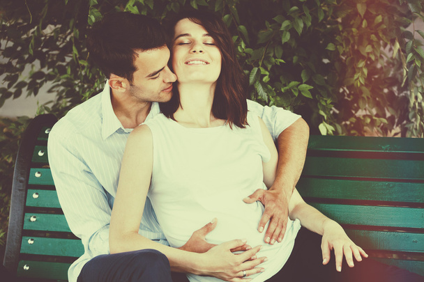 glückliche und junge schwangere Paare, die sich in der Natur umarmen. Vintage-Retro - Foto, Bild