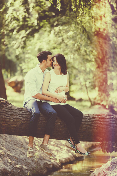 Happy and young pregnant couple hugging in nature. Vintage retro - Photo, Image
