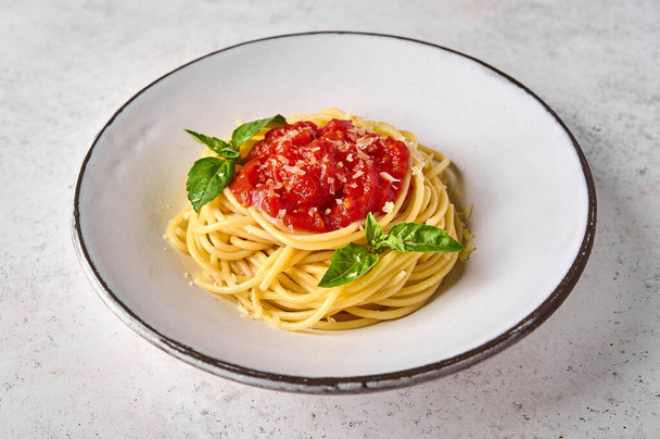 Close up spaghetti in tomato sauce, parmesan cheese and basil on white plate - Photo, image