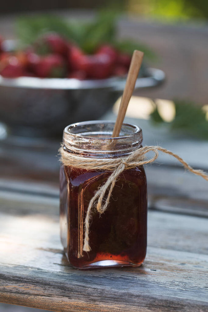 Strawberry jam in a jar on a wooden board. Fermented berries. - Foto, Bild