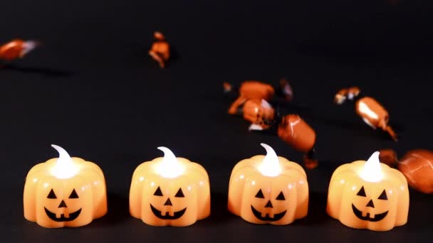 Mi sto preparando per Halloween. caramelle arancioni versano lentamente sullo sfondo nero, lanterne di zucca bagliore. - Filmati, video