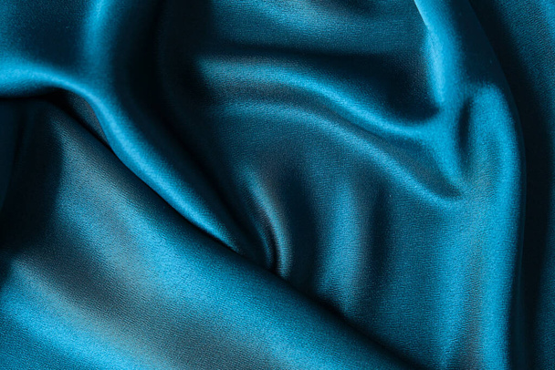 Niebieska jedwabna draperia i tkanina tapicerska z dziedzińca. Niebieska satyna, jedwabista tkanina, fala, draperia. Piękne tło tekstylne. Zbliżenie. Widok z góry - Zdjęcie, obraz
