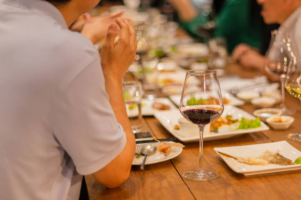 屋内での夕食会でテーブルの上に赤ワインのグラスの選択された焦点. - 写真・画像