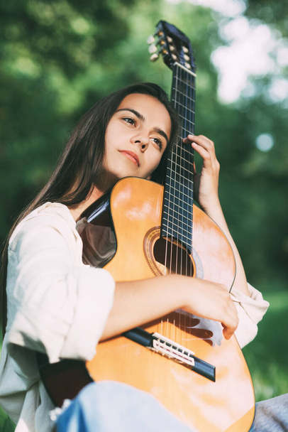 Portrait of a young girl guitarist who smiles and holds a guitar in her hands. Girl-musician, music, hobby - Zdjęcie, obraz