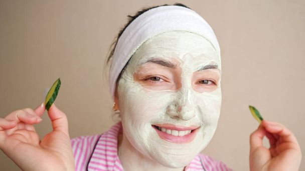 Jeune femme avec un masque sur le visage joue avec des anneaux de concombre, danse - Photo, image